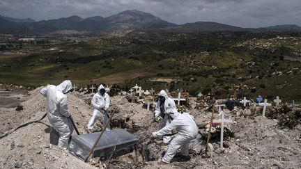 Des employés d'un cimetière de Tijuana, au Mexique, portent un équipement de protection lors de l'enterrement d'une victime du coronavirus, le 21 avril 2020. (GUILLERMO ARIAS / AFP)