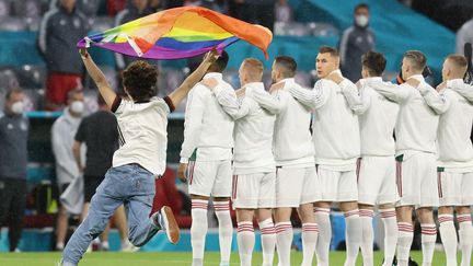 Un spectateur a pénétré sur la pelouse de l'Allianz Arena de Munich avec un drapeau arc-en-ciel, durant les hymnes avant le match Allemagne-Hongrie, le 23 juin 2021. (ALEXANDER HASSENSTEIN / POOL / AFP)