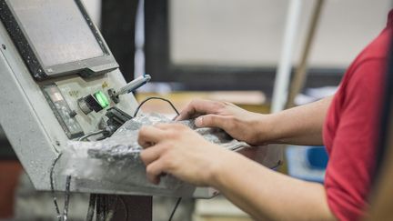 Un ouvrier utilise une machine dans une usine (illustration). (ERIC AUDRAS / MAXPPP)