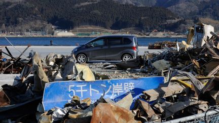 Une voiture passe devant un tas de d&eacute;bris provoqu&eacute;s par le tsunami dans la pr&eacute;fecture d'Iwate, &agrave; Ofunato (Japon), le 15 f&eacute;vrier 2012. (TORU YAMANAKA / AFP)