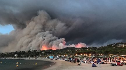 Des personnes évacuées s'installent sur la plage de Bormes-les-Mimosas (Var) alors que le feu ravage les hauteurs de la ville, le 26 juillet 2017. (MARION LEFLOUR / AFP)