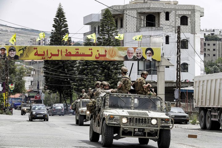 Des militaires libanais passent devant une banderole du mouvement chiite Hezbollah, le 15 mai 2022. (MAHMOUD ZAYYAT / AFP)