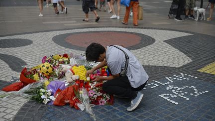 Un homme dépose des fleurs sur Las Ramblas, le 16 août 2018, un après&nbsp;les attentats qui&nbsp;ont coûté la vie à 16 personnes.&nbsp; (JOSEP LAGO / AFP)