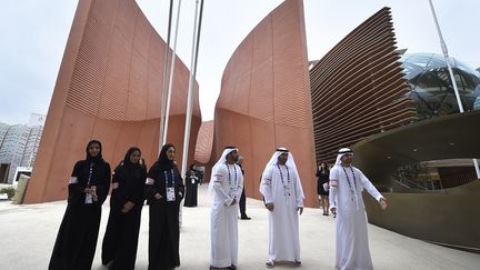 Trois femmes en noir, trois hommes en blanc : le comit&eacute; d'accueil des visiteurs au pavillon des Emirats arabes unis. (OLIVIER MORIN / AFP)