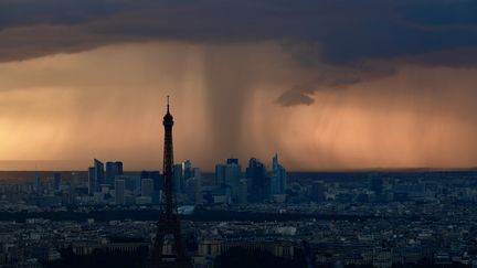 Une photo prise de l'observatoire de la Tour Montparnasse à Paris montre la tour Eiffel et le quartier de la Défense sous un large nuage de pluie, le mercredi 30 mai 2018. (PHILIPPE LOPEZ / AFP)