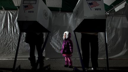 Une fillette patiente pendant que ses parents utilisent des machines &eacute;lectroniques pour exprimer leurs votes &agrave; Staten Island (New York), mardi 6 novembre 2012. (ALLISON JOYCE / GETTY IMAGES / AFP)