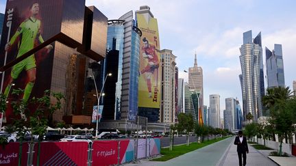 Un homme marche, seul dans les rues de Doha, au milieu des gratte-ciels, le 17 novembre 2022. (JAVIER SORIANO / AFP)