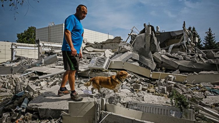 Mężczyzna siedzi na gruzach budynku po ataku rakietowym w mieście Al-Derhashi w obwodzie charkowskim, 26 sierpnia 2022 r. (SERGEY BOBOK / AFP)