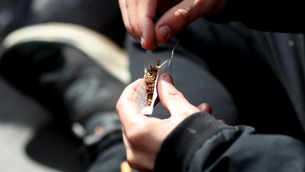 Un homme roule un joint, à Paris, le 14 mai 2016. (KENZO TRIBOUILLARD / AFP)