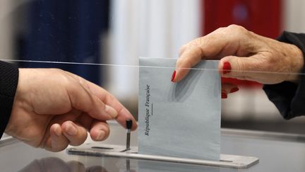 Une électrice dépose son bulletin de vote dans un bureau de vote du Touquet (Pas-de-Calais), pour le second tour des élections régionales françaises, le 27 juin 2021. (LUDOVIC MARIN / AFP)