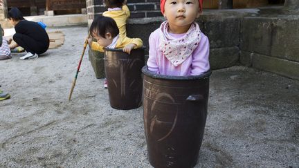 De jeunes Cor&eacute;ens jouent dans des jarres en marge du festival de cuisine traditionnelle &agrave; S&eacute;oul (Cor&eacute;e du sud), le 1er octobre 2013. (REUTERS)