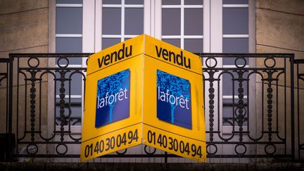 Un panneau d'agence immobilière à la fenêtre d'un appartement vendu à Paris, le 19 décembre 2017. (illustration) (LIONEL BONAVENTURE / AFP)