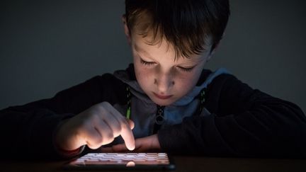 Un enfant de 8 ans joue à un jeu video sur une tablette tactile. (VICTOR TONELLI / HANS LUCAS via AFP)