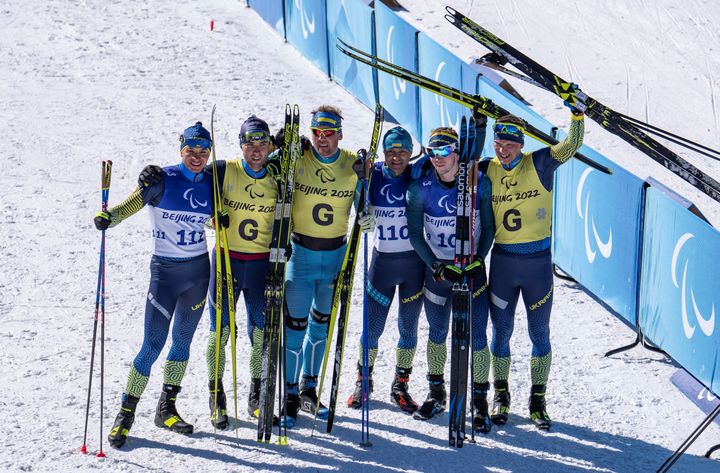 Les para biathlètes ukrainiens ont réalisé un triplé sur le sprint masculin, dans la catégorie déficient visuel. (De gauche à droite) Le médaillé d'argent Oleksandr Kazik aux côtés de son guide Serhii Kucheriavyi, le médaillé d'or Vitalii Lukianenko aux côtés de son guide Boys Babar et le médaillé de bronze Dmytro Suiarko aux côtés de son guide Oleksandr Nikonovych, posent ensemble après leur victoire, le 5 mars 2022. (THOMAS LOVELOCK / OIS / IOC / AFP)