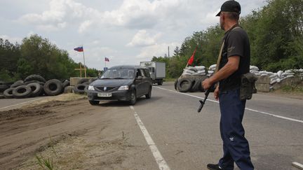 Un activiste prorusse contr&ocirc;le un&nbsp;checkpoint &agrave; la sortie du village de&nbsp;Schastya,&nbsp;&agrave; 25 km de Louhansk, dans l'est de l'Ukraine, le 14 mai 2014.&nbsp; (VALENTYN OGIRENKO / REUTERS)