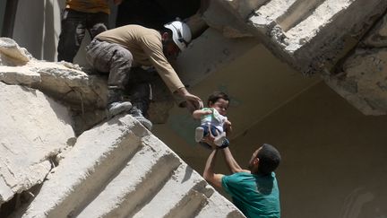 Des volontaires évacuent un bébé d'un immeuble détruit, jeudi 28 avril, dans le quartier d'al-Kalasa. (AMEER ALHALBI / AFP)