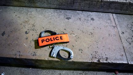 Menottes et insigne de police posé à terre en signe de&nbsp;protestation, le 14 juin 2020.&nbsp;Des policiers s'estiment stigmatisés dans un contexte de manifestations contre le racisme et les violences policières. (GABRIELLE CEZARD / HANS LUCAS VIA AFP)