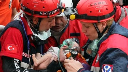 Des sauveteurs portent un b&eacute;b&eacute; de deux semaines retir&eacute; des d&eacute;combres apr&egrave;s le tremblement de terre &agrave; Ercis (Turquie), le 25 octobre 2011. (ADEM ALTAN / AFP)