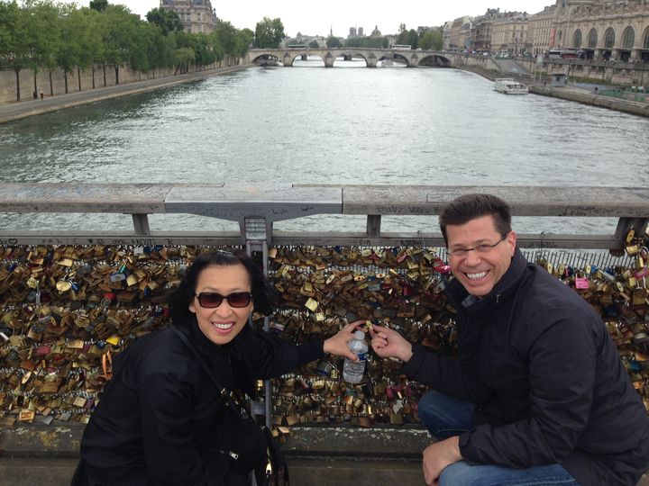 Sunny et Bill, un couple de New-Yorkais, fixent leur cadenas sur la passerelle L&eacute;opold-S&eacute;dar-Senghor. (ILAN CARO / FRANCETV INFO)