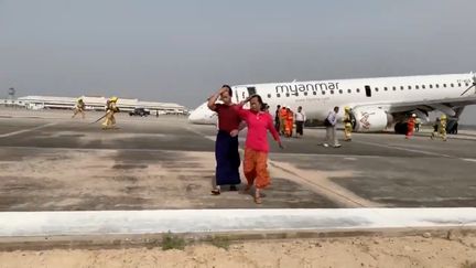 Des passagers évacués d'un avion de&nbsp;Myanmar Airlines après son atterrissage d'urgence sans train avant, le 12 mai 2019 à Mandalay (Myanmar, Birmanie). (REUTERS)