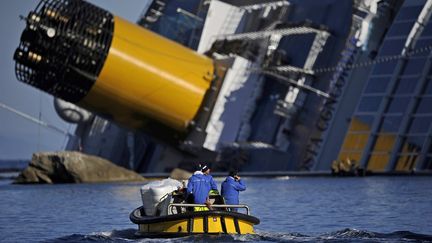 Des techniciens longent l'&eacute;pave du "Concordia", le 26 janvier 2012 pr&egrave;s de l'&icirc;le du Giglio (Italie). (FILIPPO MONTEFORTE / AFP)