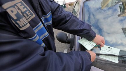 Un policier municipal dépose un PV électronique sur une voiture à Lorient (Morbihan), le 6 décembre 2013. (Photo d'illustration) (MAXPPP)