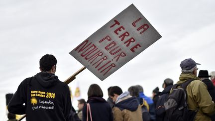 Un opposant a la construction de l'aéroport Notre-Dame-des-Landes brandit un panneau : "la terre pour nourrir", le 13 octobre 2015 à Nantes. (LOIC VENANCE / AFP)