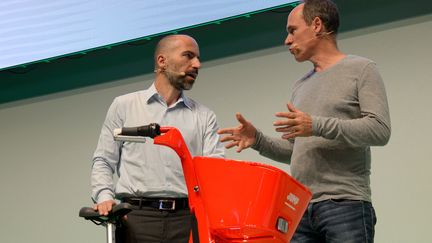 Le patron d'Uber,&nbsp;Dara Khosrowshahi (à gauche), présente le vélo de sa compagnie, à Berlin (Allemagne), lors de la conférence NOAH,&nbsp; le 6 juin 2018. (SINA SCHULDT / DPA)