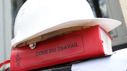 Un casque de chantier sur un code du travail. Photo d'illustration. (CHRISTOPHE BERTOLIN / MAXPPP)