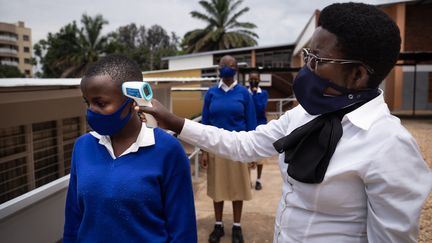 Des élèves du lycée Notre-Dame de Citeaux à Kigali (Rwanda) se font prendre la température avant d'entrer en classe, le 2 novembre 2020. (SIMON WOHLFAHRT / AFP)