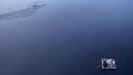 Un homme sur un radeau de fortune tente de collecter des objets parmi les d&eacute;tritus flottant sur la Yamun&acirc; &agrave; New Delhi (Inde), le 3 janvier 2012. (ADNAN ABIDI / REUTERS)