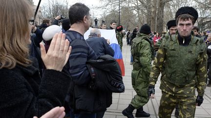 Des personnes applaudissent des volontaires pro-russes charg&eacute;s de prot&eacute;ger le Parlement de Crim&eacute;e, pendant une manifestation pro-russes &agrave; Simferopol, jeudi 6 mars 2014.&nbsp; (ALEXANDER NEMENOV / AFP)