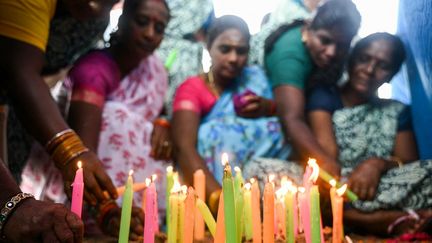 Des femmes allument des bougies sur la plage de Pattinapakkam, en Inde. (R.SATISH BABU / AFP)