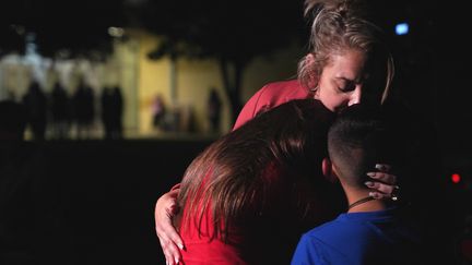 Une mère étreint ses enfants devant le centre&nbsp;civique Willie de Leon où ont été transférés des écoliers indemnes après la fusillade qui a touché leur école primaire, le 24 mai à Uvalde au Texas, faisant&nbsp;plus de 20 morts. (ALLISON DINNER / AFP)