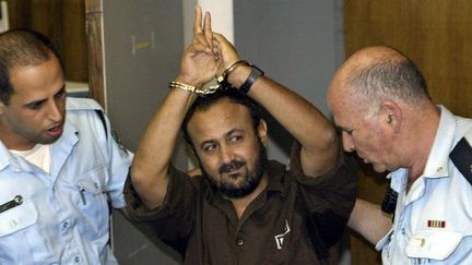 Marwan Barghouti, poignets menottés, fait le V de la victoire en allant au tribunal de Tel Aviv où se tient son procès, le 20 mai 2004. (DAVID SIVERMAN /  AFP)