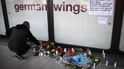 Un homme allume des bougies en hommage aux victimes du crash de l'A320 de la Germanwings, devant un comptoir de la compagnie, le 25 mars 2015 &agrave; Berlin (Allemagne).&nbsp; (ZHANG FAN / AFP)