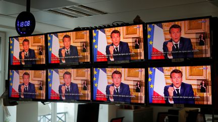 Emmanuel Macron diffusé sur des écrans à Paris lors d'une prise de parole&nbsp;sur la crise sanitaire, le 13 avril 2020. (CHARLES PLATIAU / REUTERS)