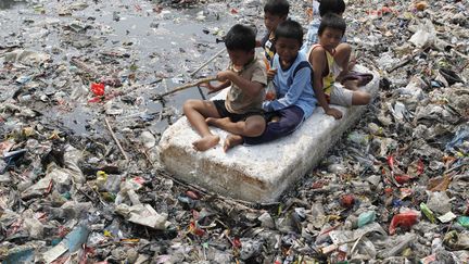 Des enfants jouent au milieu d'une rivi&egrave;re encombr&eacute;e de d&eacute;tritus dans un bidonville de Djakarta (Indon&eacute;sie), le 19 septembre 2012. (ENNY NURAHENI / REUTERS)