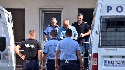 La police escorte Gheorghe Dinca, suspecté du meurtre d'une adolescente à Craiova, en Roumanie, le 30 juillet 2019.&nbsp; (BOGDAN DANESCU / AFP)