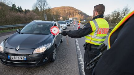 Des policiers allemands contrôlent un véhicule tentant de passer la frontière depuis la Moselle, à Sarrebruck (Allemagne), le 16 mars 2020, lors du premier confinement lié au Covid-19. (OLIVER DIETZE / DPA / AFP)