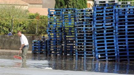 Une personne évacue l'eau au MIN de Cavaillon inondée à la suite des orages qui ont frappé le Vaucluse. (AFP - Gerard Julien)