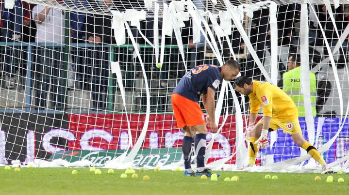 Les joueurs de Montpellier ramassent des balles de tennis jet&eacute;es sur le terrain par des supporters d'Auxerre, en signe de m&eacute;contentement. (JEAN BAPTISTE QUENTIN / MAXPPP)