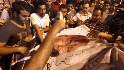 Des Egyptiens s'en prennent &agrave; une affiche du candidat &agrave; la pr&eacute;sidentielle Ahmed Chafik, au Caire (Egypte), le 28 mai 2012. (KHALED DESOUKI / AFP)