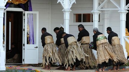 Des hommes se prosternent avant d’entrer dans la salle du trône du Palais Royal, orné de rubans noirs et violets, où repose le corps du défunt. (AFP PHOTO / Torsten BLACKWOOD)