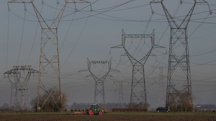 Un fermier conduit son tracteur dans un champ qui longe des lignes électriques à&nbsp;Fessenheim (Haut-Rhin), le 6 décembre 2019. (SEBASTIEN BOZON / AFP)