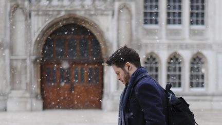 Un Londonien passe devant le Guildhall, l'ancien hôtel de ville britannique, alors qu'il neige abondamment, le 26 février 2018.&nbsp; (DANIEL SORABJI / AFP)