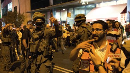 Un m&eacute;decin et des membres des forces de s&eacute;curit&eacute; isra&eacute;liennes sur le site d'une attaque, &agrave; la gare routi&egrave;re de J&eacute;rusalem, mercredi 14 octobre 2015. (MENAHEM KAHANA / AFP)