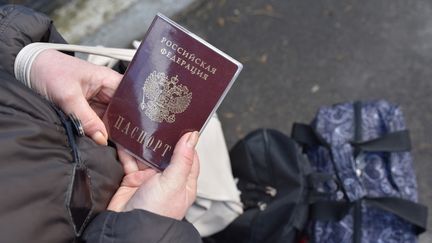 Une femme tient un passeport russe dans ses mains, à Donetsk en Ukraine, le 19 février 2022. (STR / AFP)