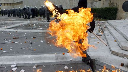 Un manifestant lance un cocktail molotov sur des policiers devant le parlement &agrave; Ath&egrave;nes (Gr&egrave;ce), le 6 d&eacute;cembre 2011. (YANNIS BEHRAKIS / REUTERS)