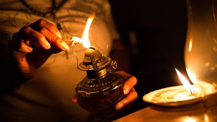 Un habitant allume une lampe à pétrole à Caracas, le 9 mars. (CRISTIAN HERNANDEZ / AFP)